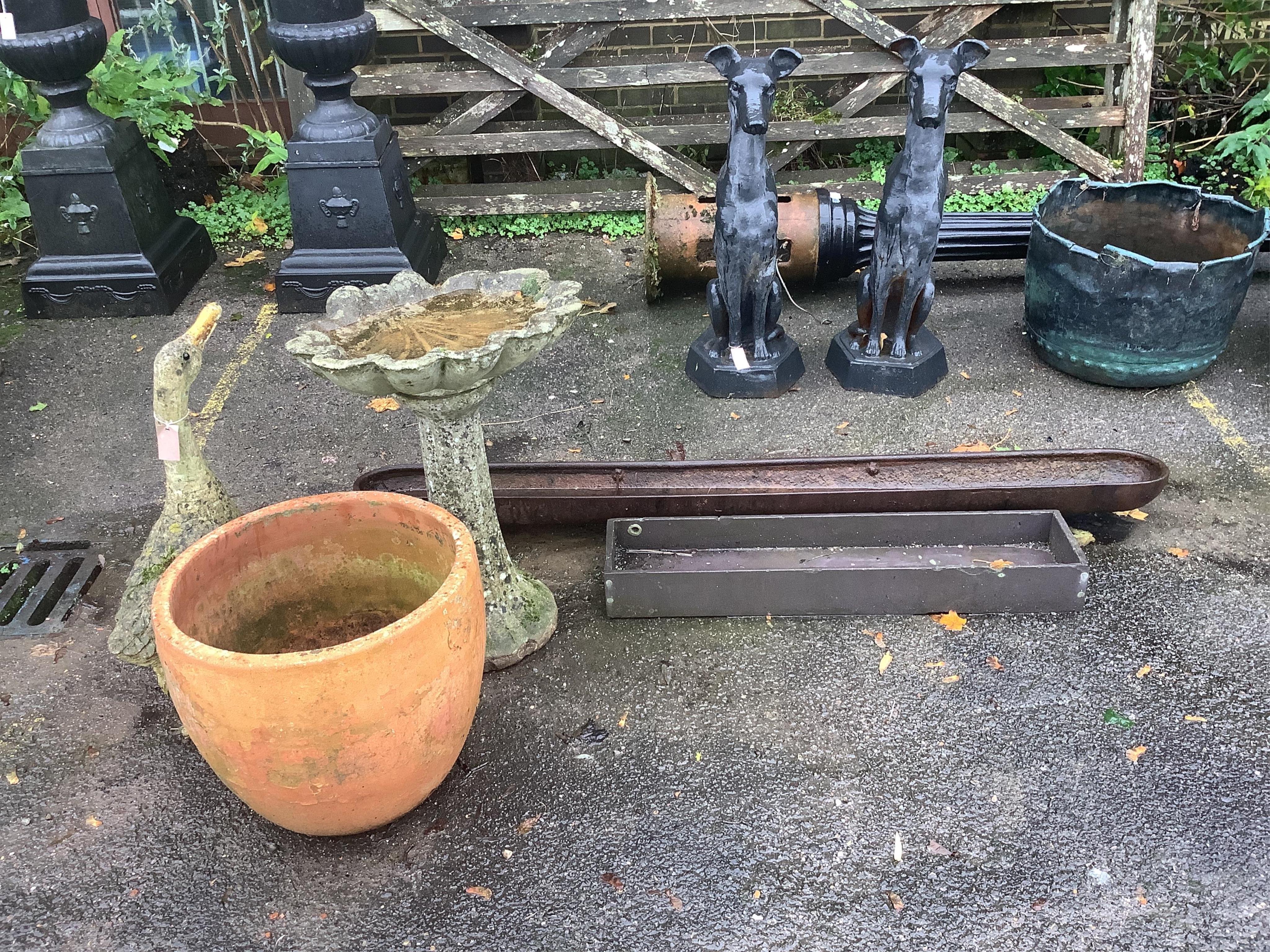 A reconstituted stone scallop shell bird bath, height 71cm, three reconstituted stone garden ornaments, a terracotta planter and two feeding troughs. Condition - fair